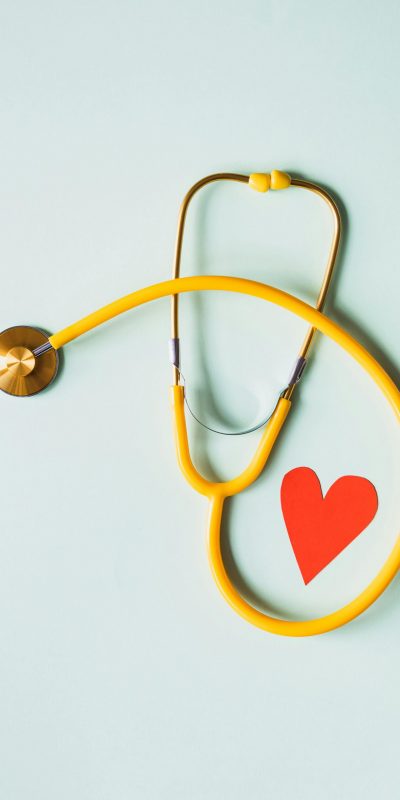 A yellow stethoscope with a red paper heart next to it.